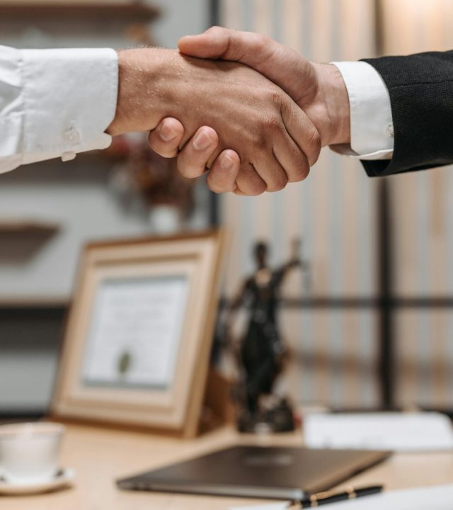 Close-up of a handshake between two professionals in a modern office setting, emphasizing partnership and agreement.